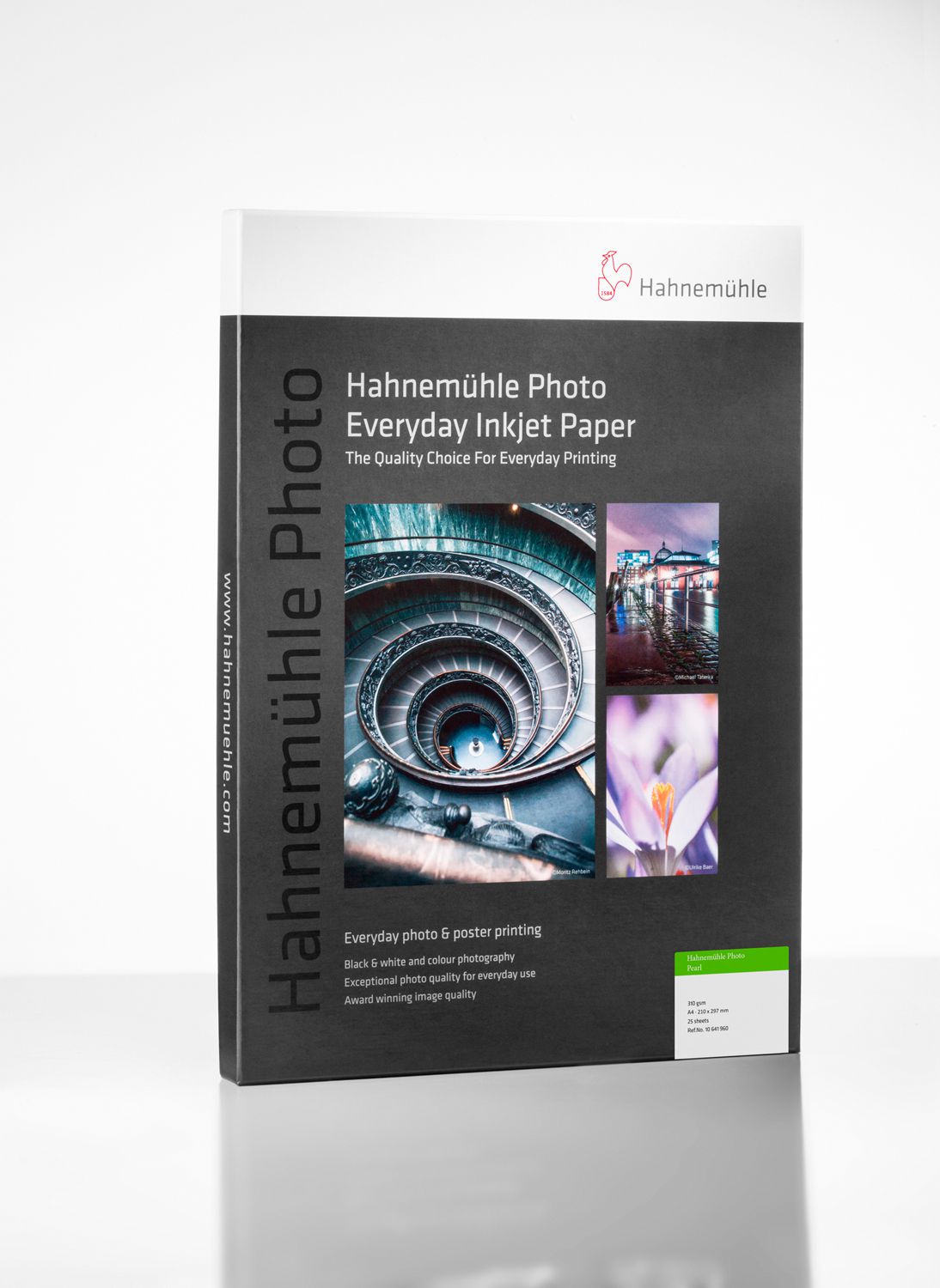 A box of Hahnemuhle Photo Pearl 310 photo paper with a gray design, product details, and images of a staircase, flower, and ferris wheel stands upright on a white surface.
