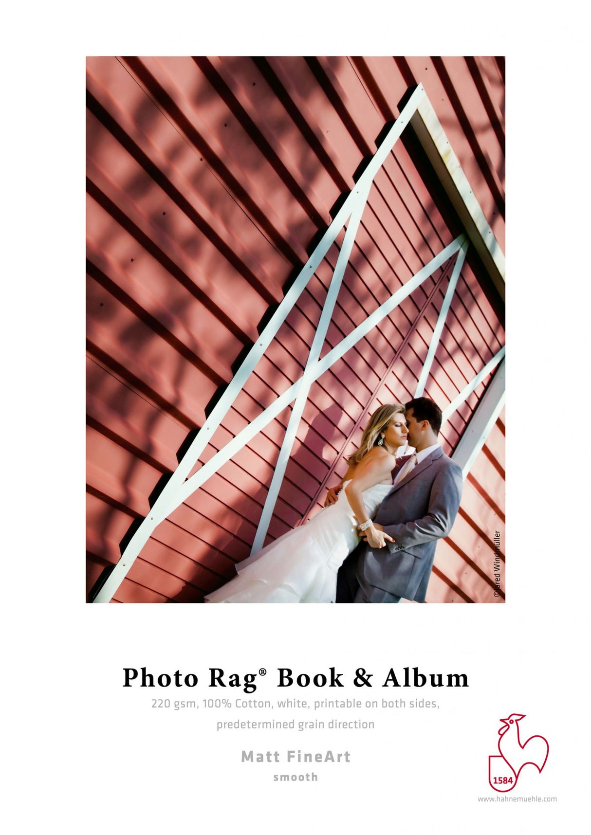 A bride and groom embrace before a red barn on a sample page for the Hahnemuhle Photo Rag® Book & Album—ideal for creating stunning books and albums with double-sided photo paper.