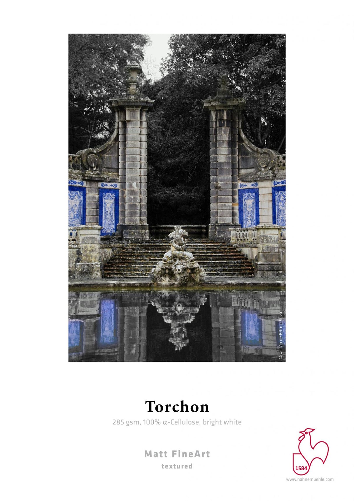A grand stone fountain and gate with blue and white tilework are mirrored in still water. Vibrant tile colors stand out against grayscale, showcasing the archival-quality vibrancy of Hahnemuhle's Hahnemühle Torchon paper.