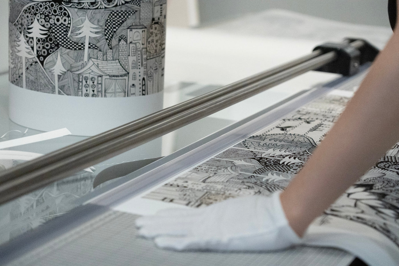 A person wearing white gloves is trimming an archival print