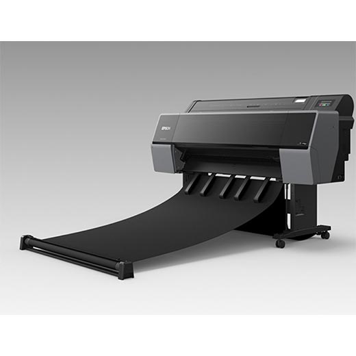 The Epson SureColor P7570 24” Wide Printer (SCP7570SE) by Epson stands on wheels, printing a wide black sheet with UltraChrome PRO12 Ink onto a horizontal tray in a gray, gradient studio.