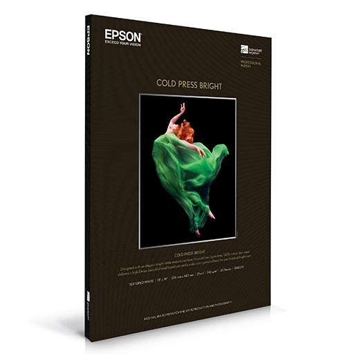 A box of Epson Cold Press Bright fine art paper by Epson displays a dynamic dancer in a green dress leaping on a black background. The packaging is black with white text and product details.