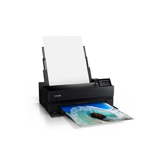 The image shows an Epson SureColor P900 17” Wide Photo Printer with a piece of colorful artwork being printed. The printer is black with a LCD Touchscreen display, and it's producing a vibrant color print.