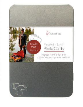 The Hahnemuhle FineArt Pearl tin holds 30 premium 4.0 x 5.9 in inkjet photo cards (285 gsm, pearl finish, 100% cellulose) and features a label with a man and violin case by a lake—ideal for creative projects.