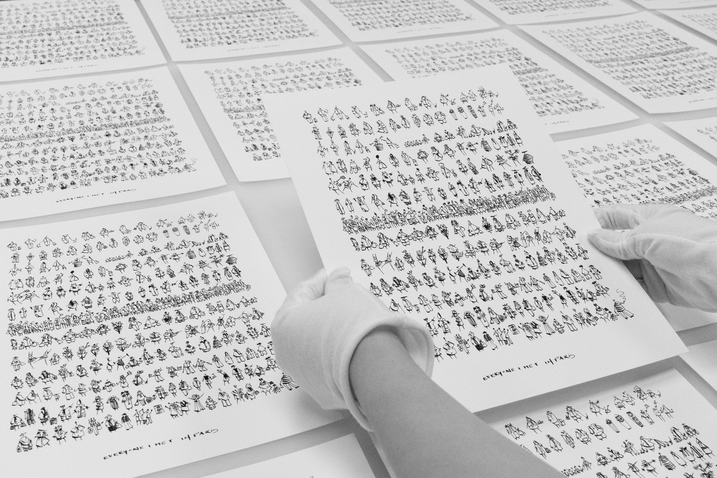 Hands holding a sheet of printed characters with a grid of similar sheets in the background.