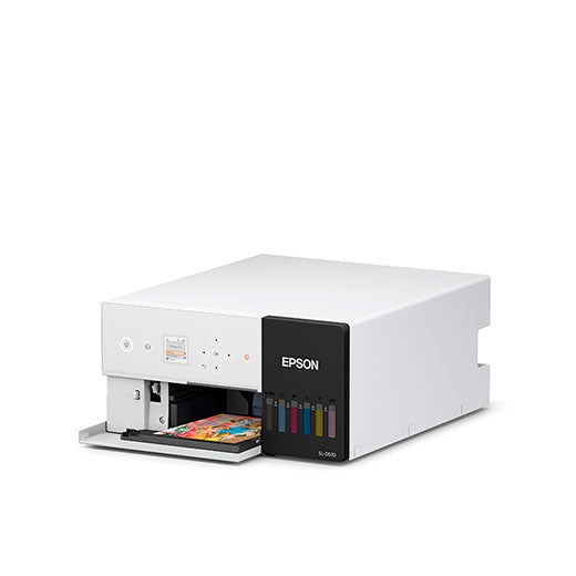 The Epson SureLab D570 Professional Minilab Photo Printer (SLD570SE) by Epson, a compact white model with a front panel ink level display, is printing a vibrant photo against a plain white background.
