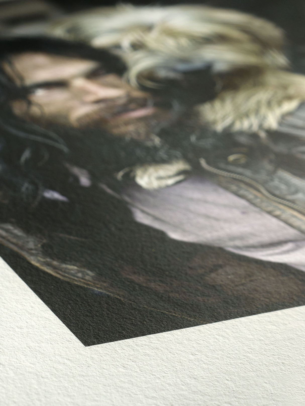 A close-up of a printed artwork depicting a bearded man with long dark hair in a fur-collared jacket on Hahnemühle Agave Paper by Hahnemuhle, where the eco-friendly agave-fibre texture is visible in the foreground.