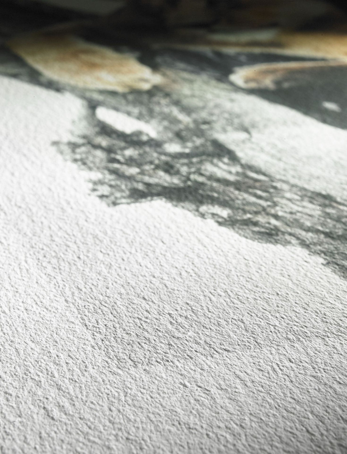 Close-up of Hahnemühle German Etching® paper by Hahnemuhle, featuring textured surface with gray and beige paint washes forming an abstract, unfinished design.
