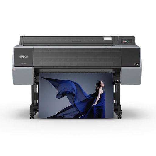 The Epson SureColor P9570 44” Wide Printer (SCP9570SE) uses UltraChrome PRO12 Ink to print a vibrant, high-res image of a woman in a blue dress on a gray background, shown emerging from the front—perfect for professional photography.